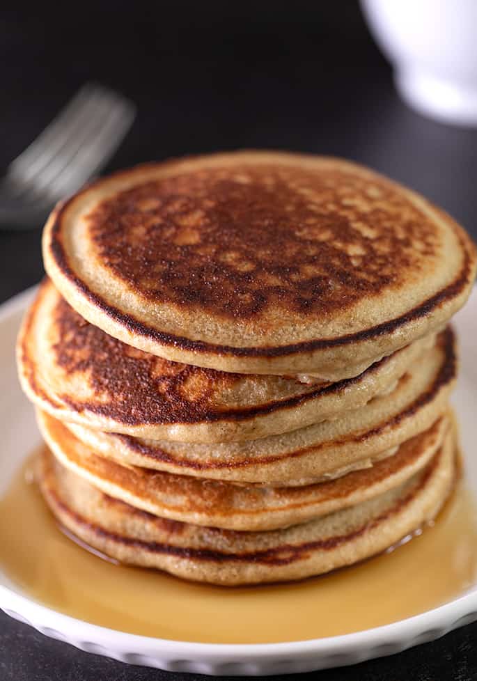 Protein pancakes in a stack on a small plate with syrup