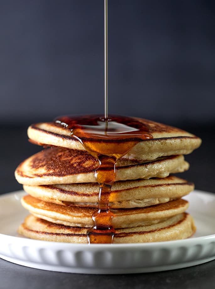 Syrup pouring over top of stack of protein pancakes