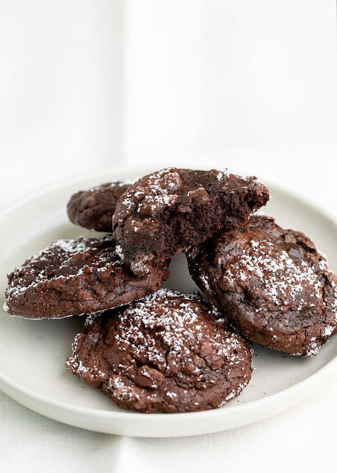 5 chocolate cookies on a small white plate one with a bite taken