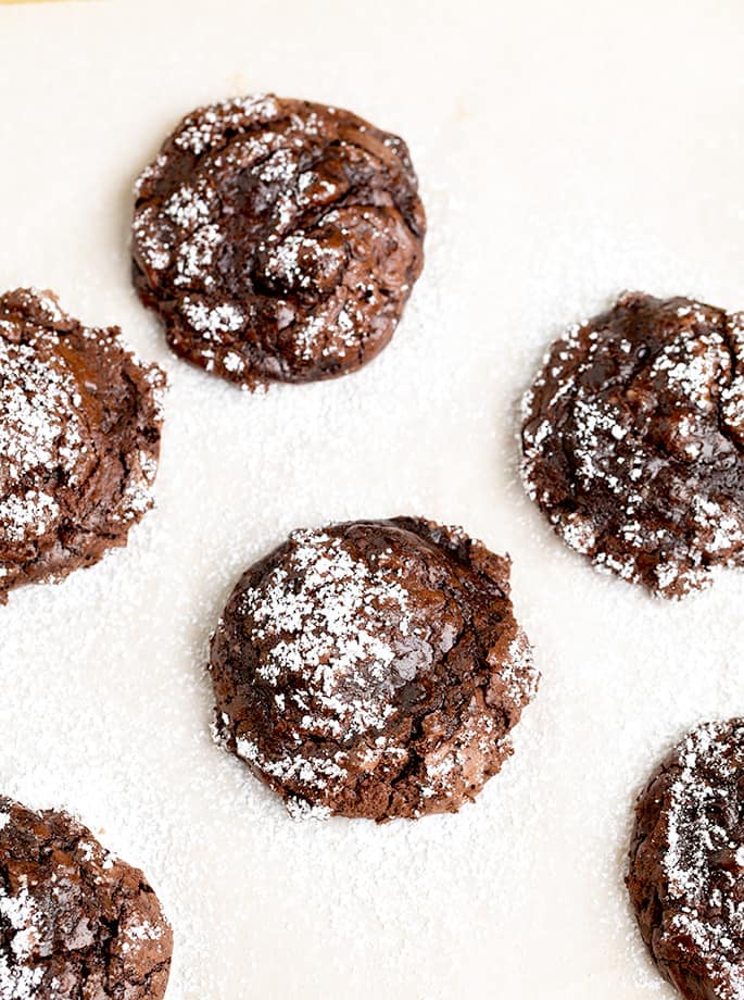 Overhead image of 6 flourless chocolate cookies on white paper