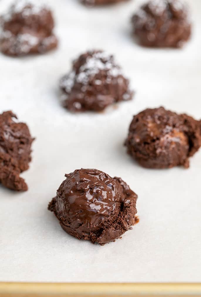 Raw mounds of flourless chocolate cookie dough on white paper