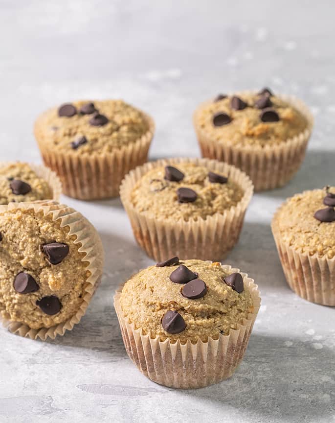 Light brown muffins with chocolate chips in light brown muffin liners that are made with quinoa flakes as an oat substitute