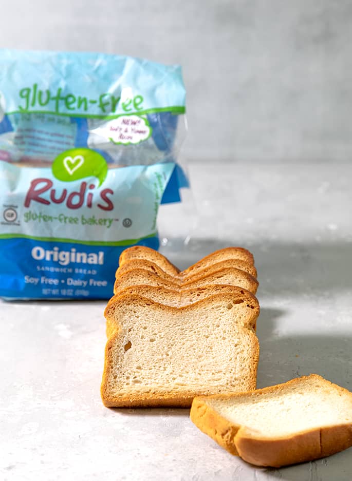 6 slices of baked bread on light gray surface with blue plastic package with word "Rudi's" in background