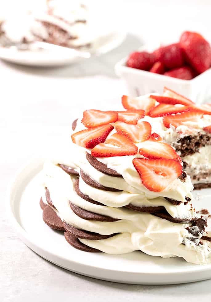 A closeup image of a chocolate wafer cookie icebox cake with berries on top