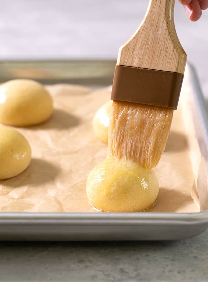 A pastry brush on top of a raw ball of pan de bono