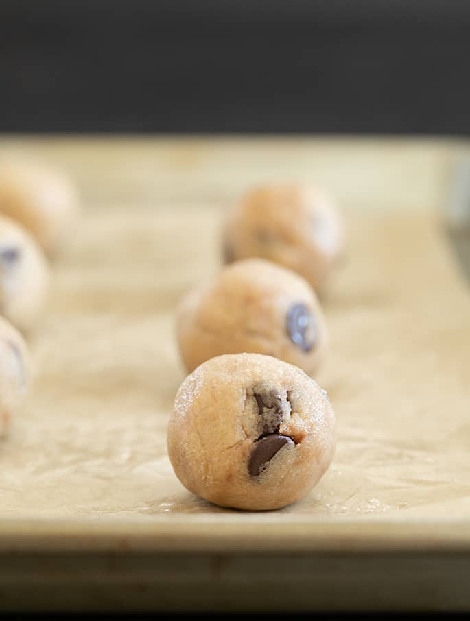 Raw balls of Mrs. Fields Chocolate Chip Cookie dough on tray