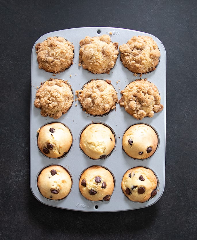 Overhead image of 12 gluten free muffins, half with crumble and half light brown with chocolate chips