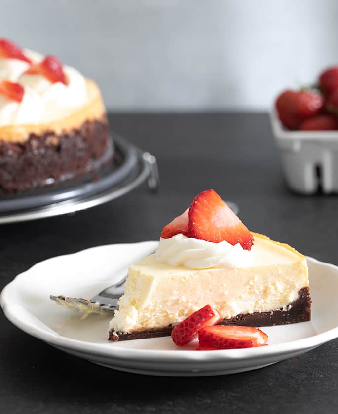 slice of gluten free cheesecake with berries on white plate with fork