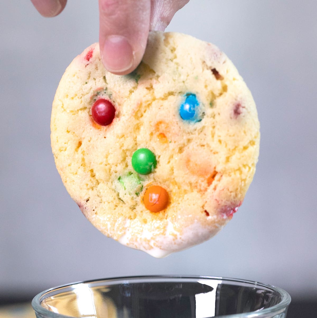 Light yellow cookie with miniature M&Ms held in fingers