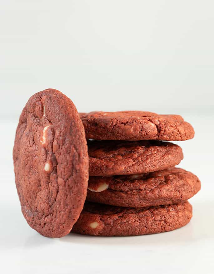 Stack of 4 red velvet cookies with one more standing up leaning against the stack