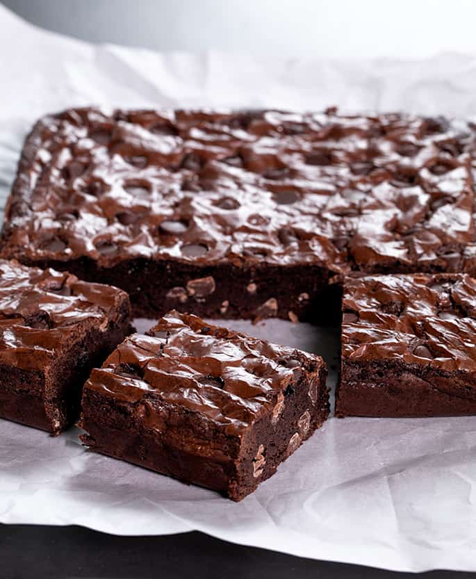 closeup image of sliced brown squares with chocolate chips on white paper