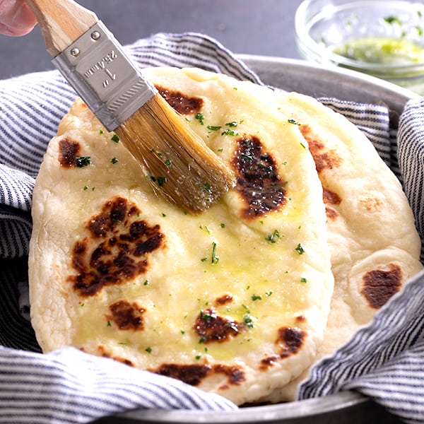 gluten free naan in striped towel with pastry brush