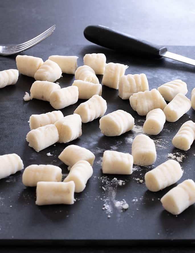 light tan dumplings on black surface with fork in background