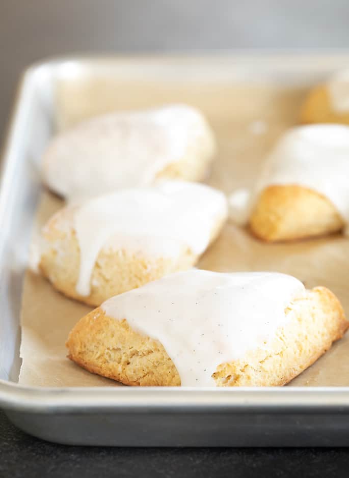 Miniature vanilla scones with white icing on a tray