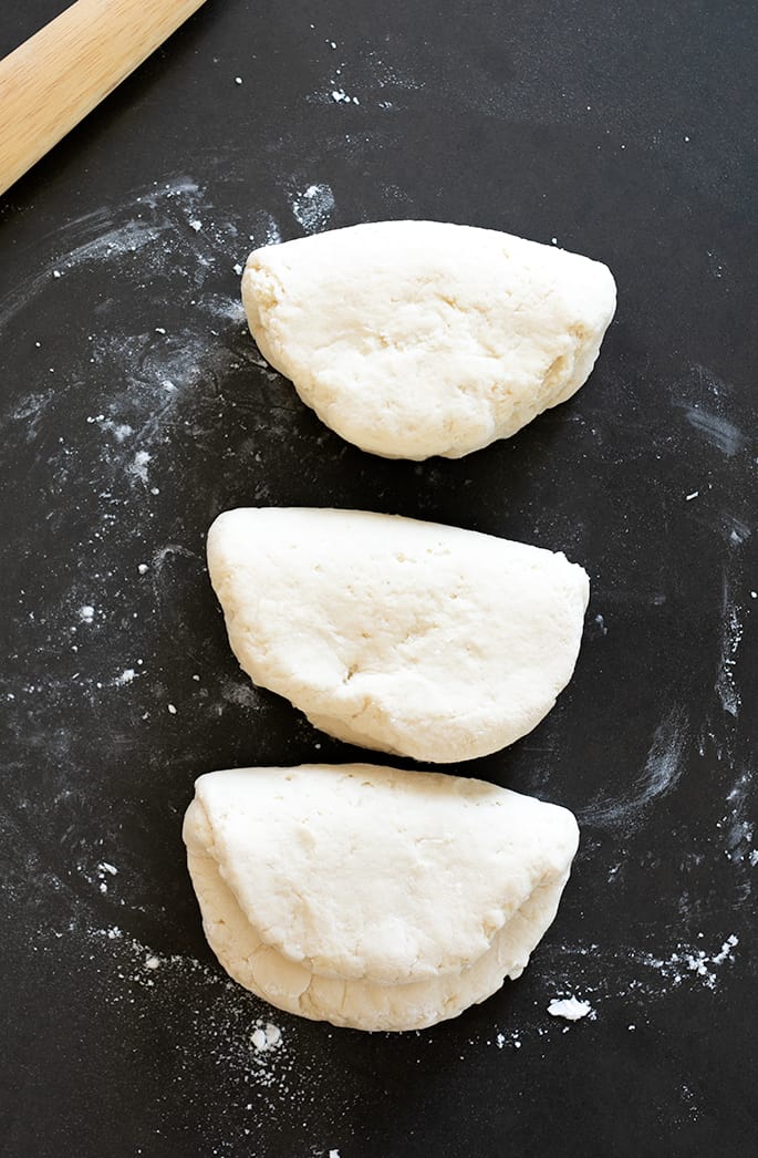 Three folded over pieces of raw bread dough on a board