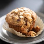 gluten free morning glory muffin in liner on gray small plate with one bite taken