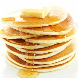 small image stack of 10 gluten free pancakes with a pat of butter on top and syrup flowing down