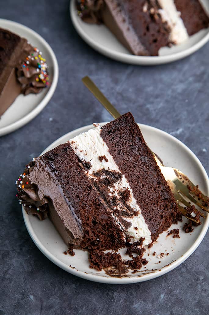 3 Slices of chocolate cake with ice cream in center on small white plates