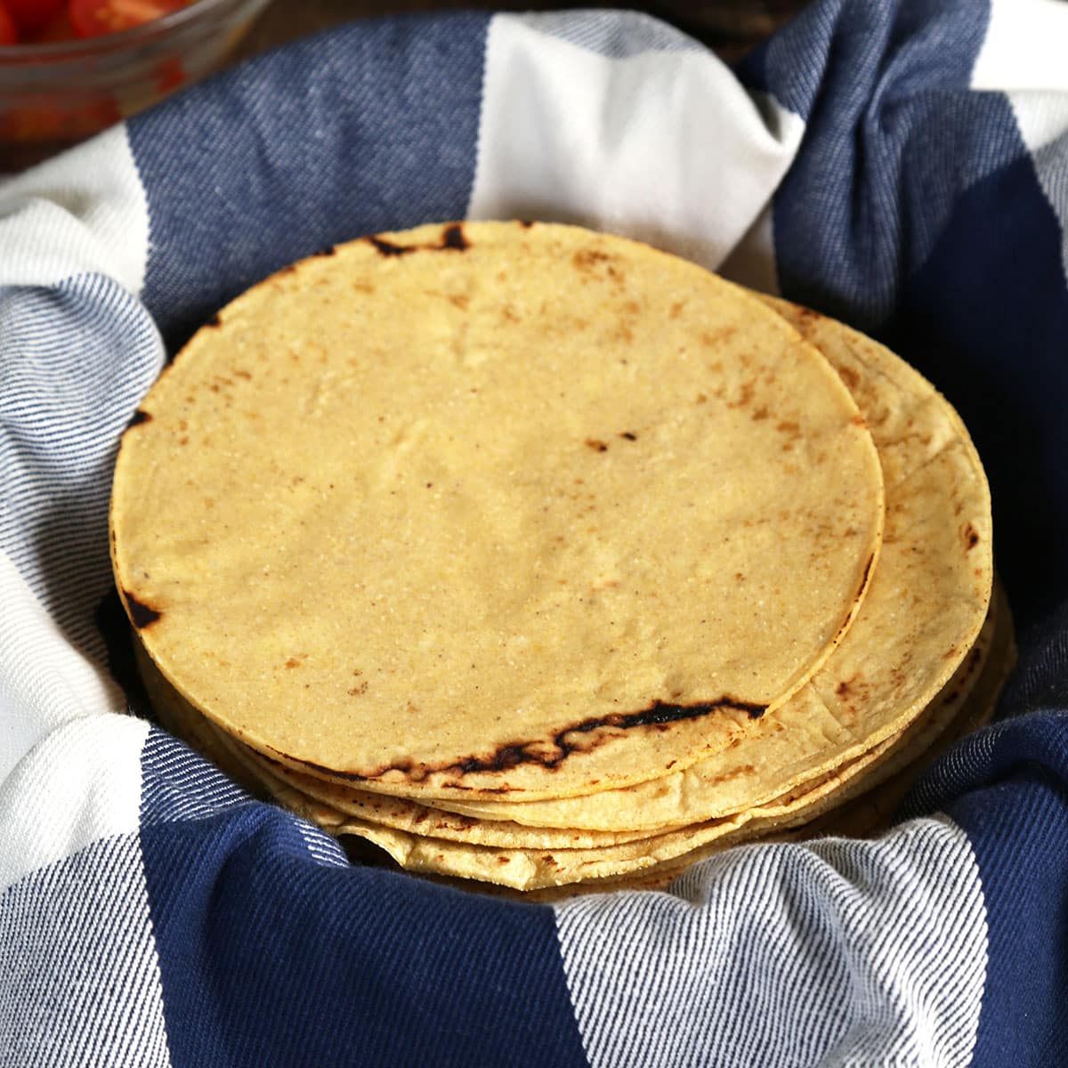 stack of 4 yellow gluten free corn tortillas on checkered blue cloth