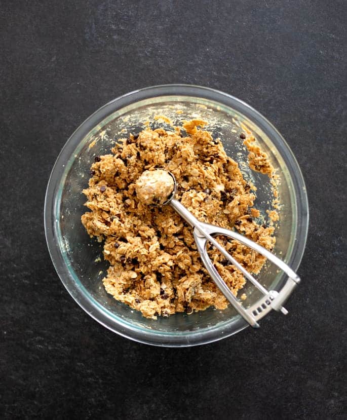 A glass mixing bowl filled with the combined protein ball ingredients.