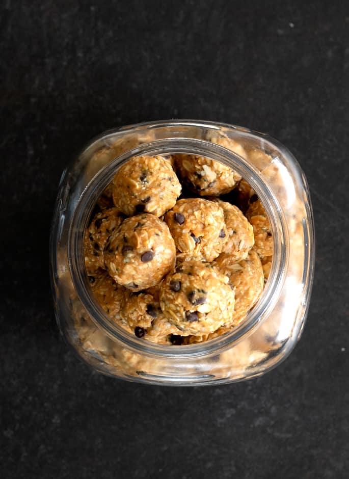 overhead image of protein balls with oats in glass jar on black surface