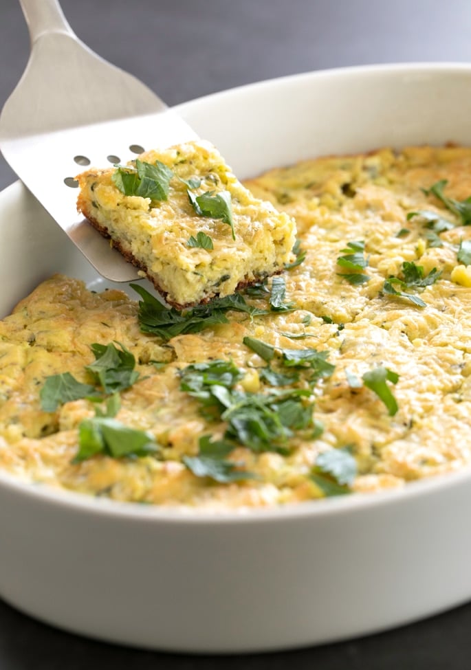 A spatula taking a square of zucchini parmesan bake from a dish