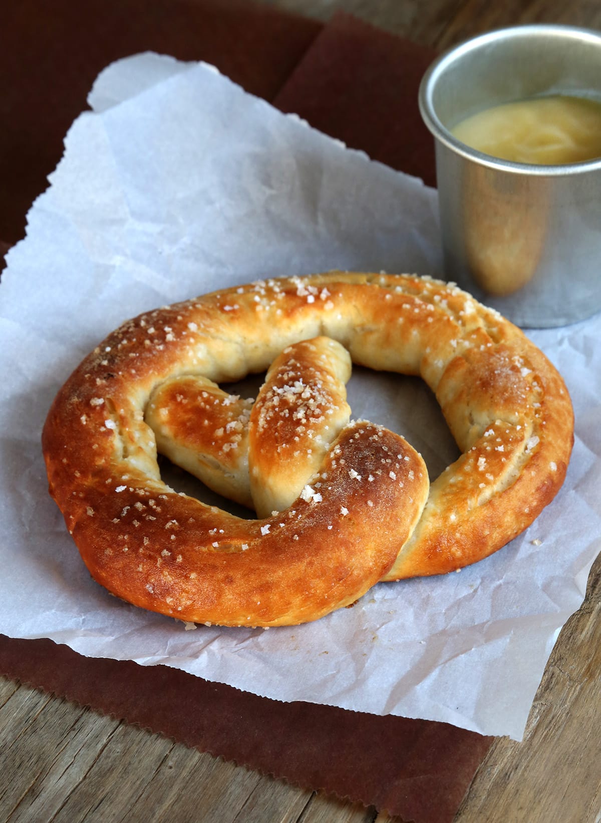 One baked gluten free soft pretzel on white parchment on a table