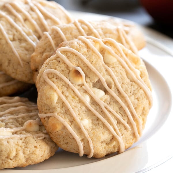 4 gluten free apple cookies with tan drizzled glaze and white chocolate chips on white platter