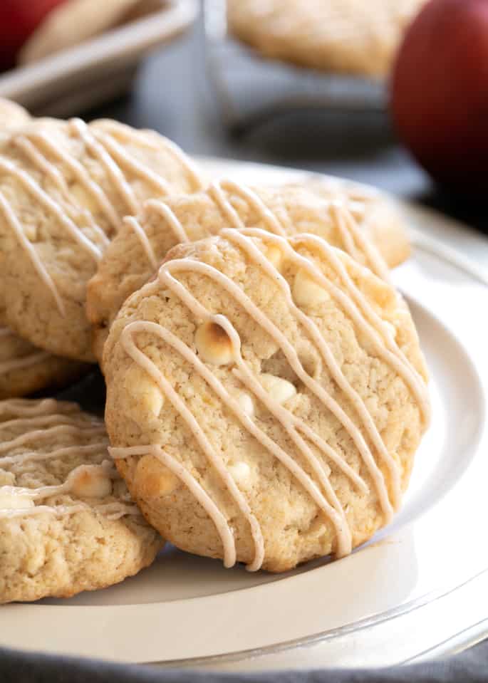 A close up of gluten free apple pie cookies on a platter with icing drizzle.