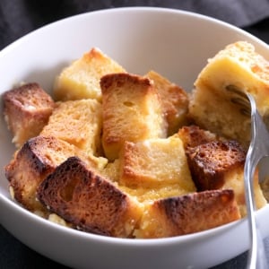 closeup image of gluten free bread pudding in white bowl with fork