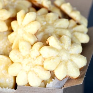 yellow flower shaped gluten free butter cookies coming out of brown kraft box