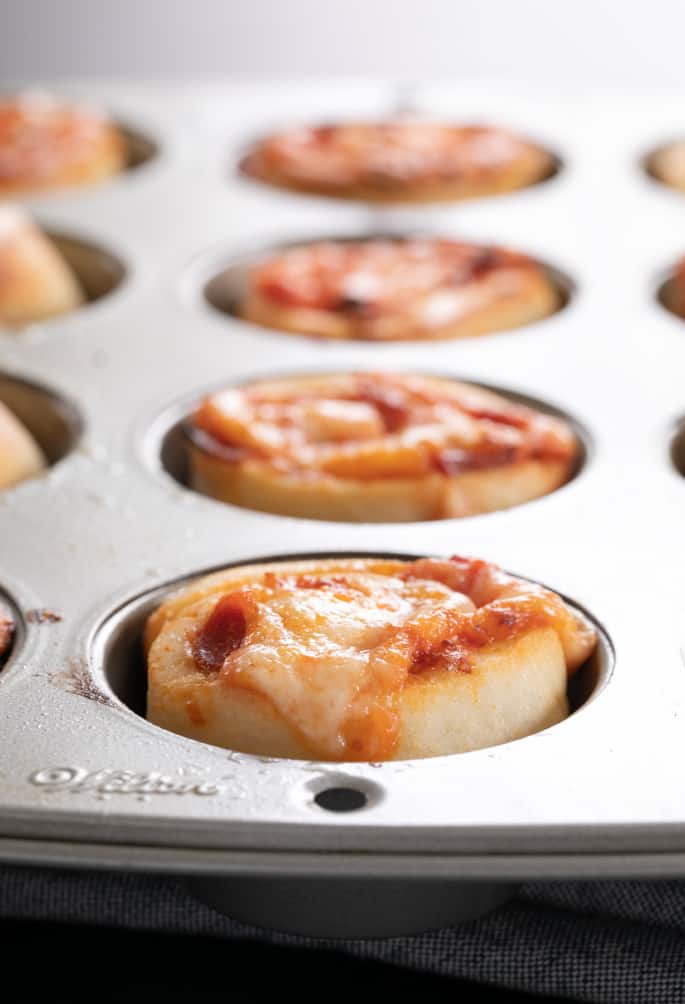 Gluten free pizza pinwheels pictured baked in muffin tin wells.