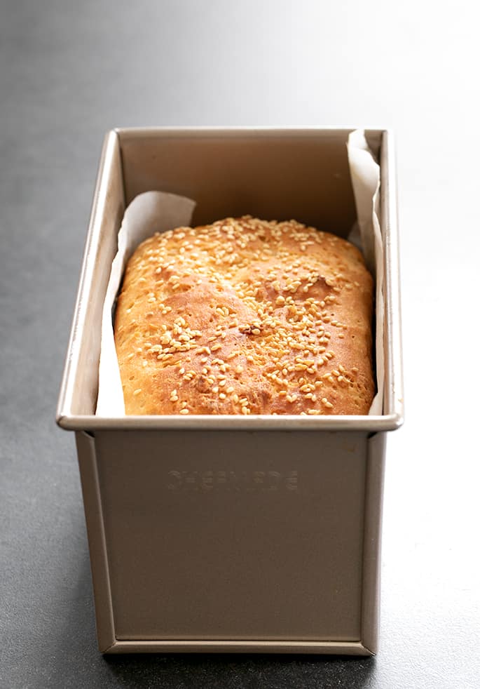 Browned top of sandwich bread with seeds shown baked in pan