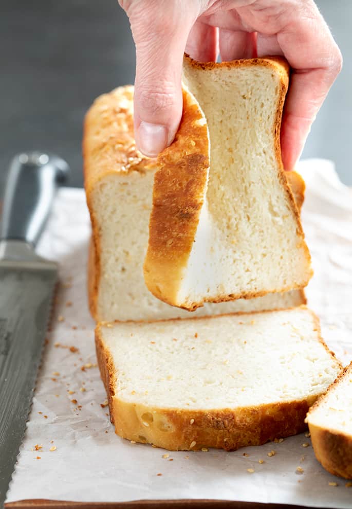 Gluten free white sandwich bread with seeds being squeezed to show soft texture