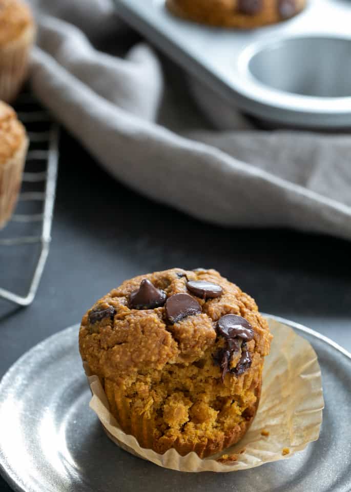 Healthy pumpkin breakfast muffins on a plate with a bite taken.