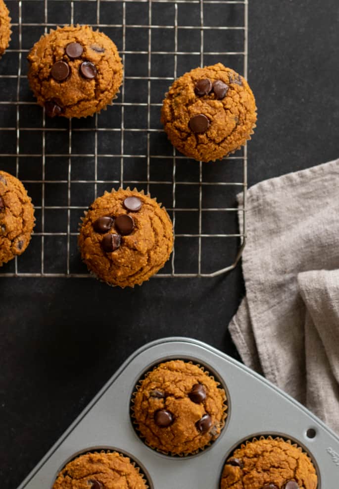 Overhead image of Healthy pumpkin breakfast muffins in muffin tin and cooling on wire rack.