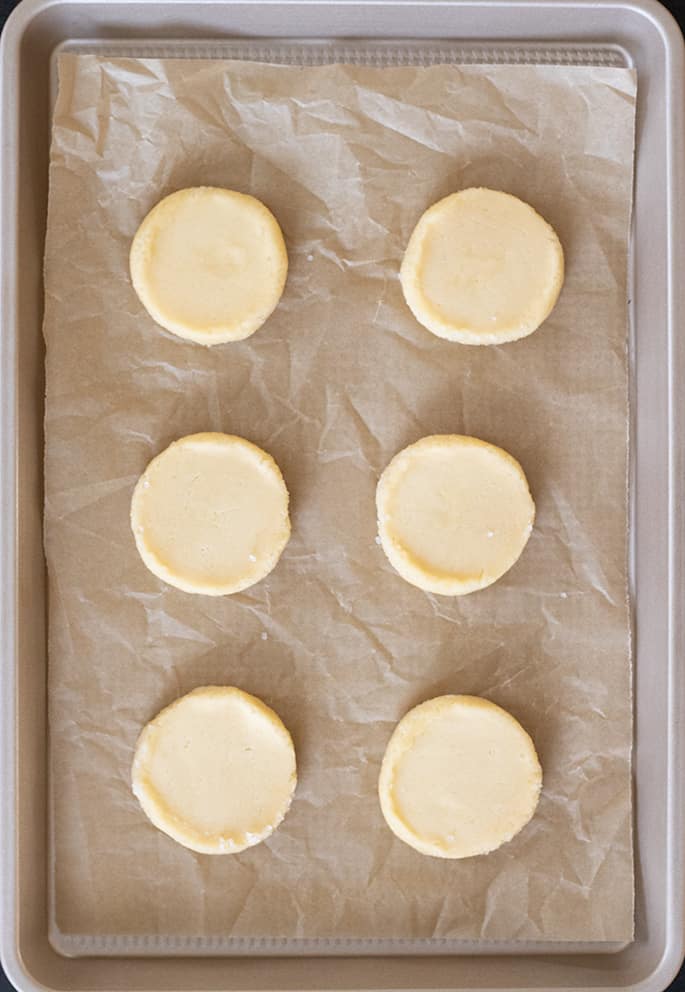 Raw, shaped gluten free sable cookies on a baking sheet.