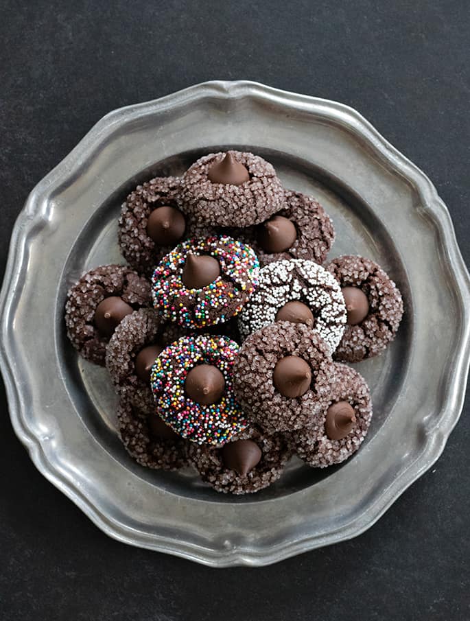 Overhead image of platter of gluten free chocolate kiss cookies, some with nonpareils and others with coarse sugar on the outside.