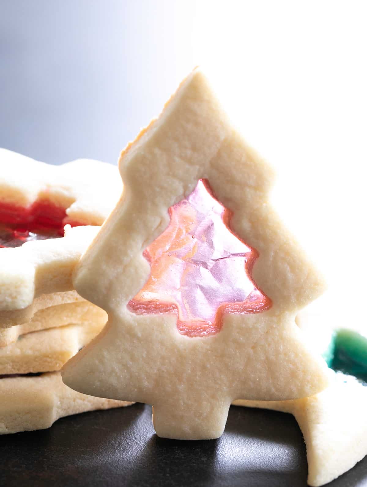 one stained glass sugar cookie shaped like a Christmas tree standing up