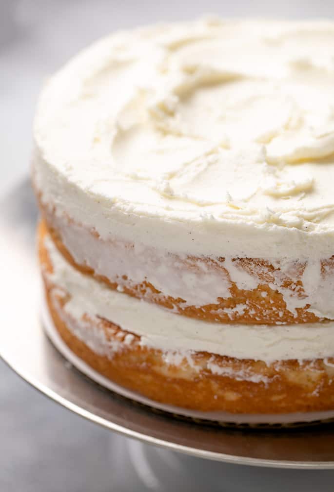 2 layer vanilla cake with white frosting in center and on top on metal turntable