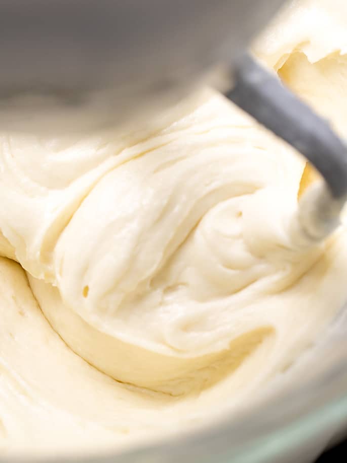 Vanilla cake batter being beaten in a stand mixer with paddle attachment