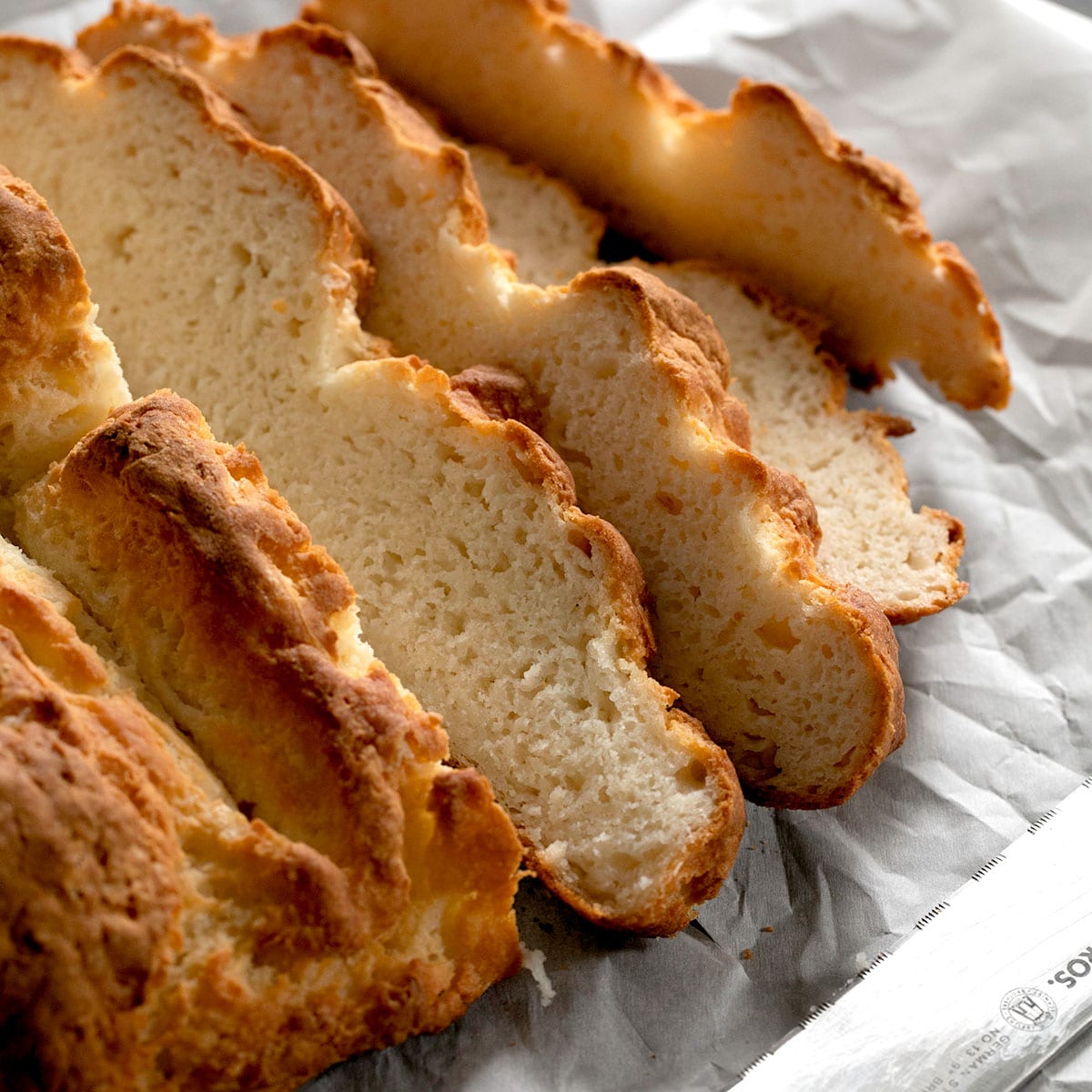 5 slices of savory gluten free Irish soda bread on white paper with bread knife