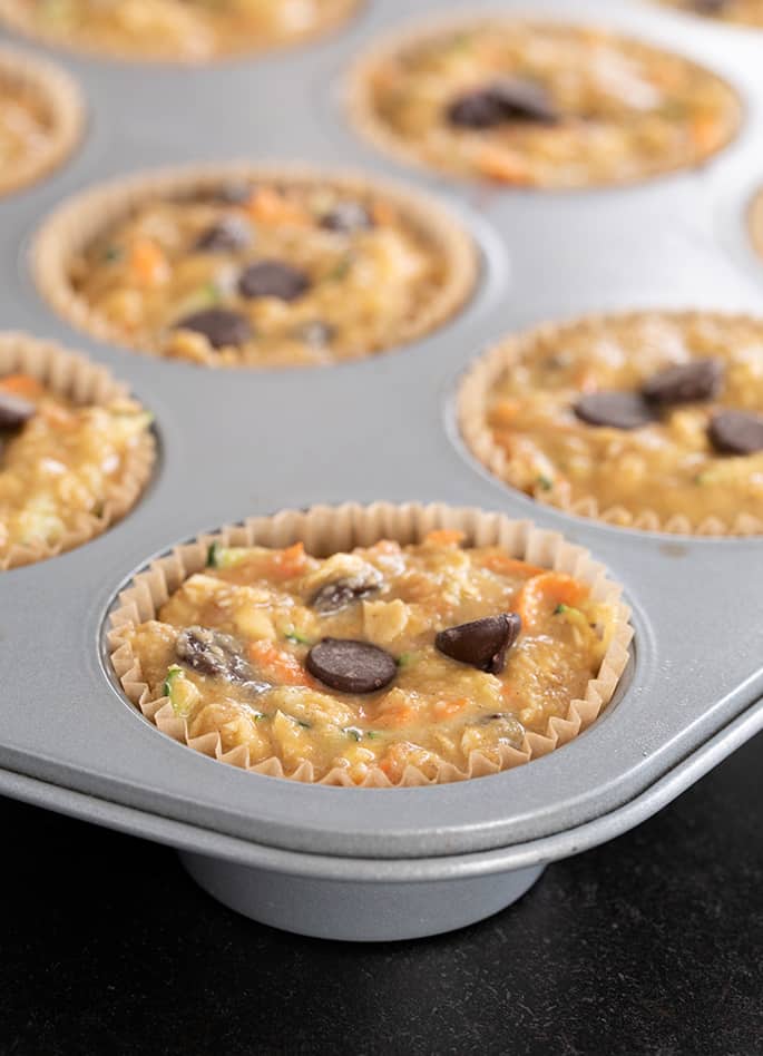 Superfood muffins raw in the wells of a muffin tin, ready to be baked. 