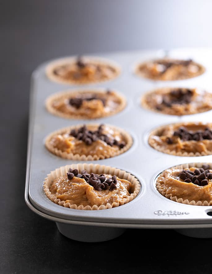 Flourless peanut butter muffins, made with no flour, no banana, and no dairy, pictured raw in the muffin tin, ready for the oven.