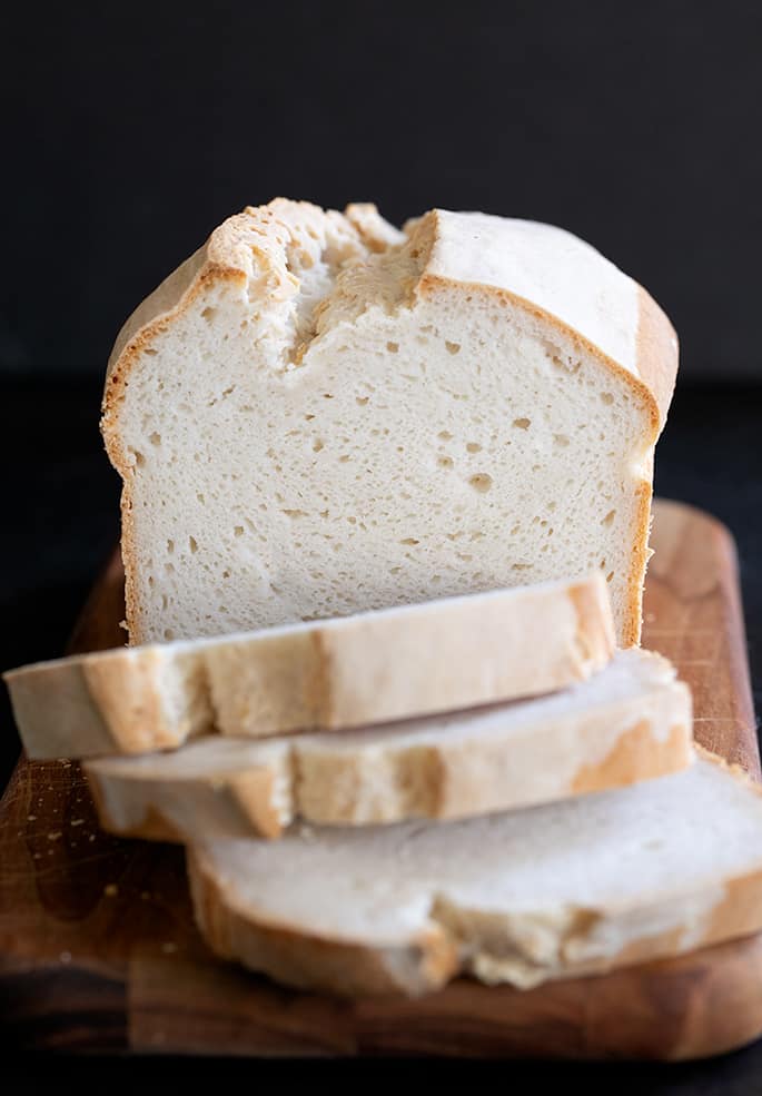 A loaf of gluten free sourdough bread, sliced and whole.