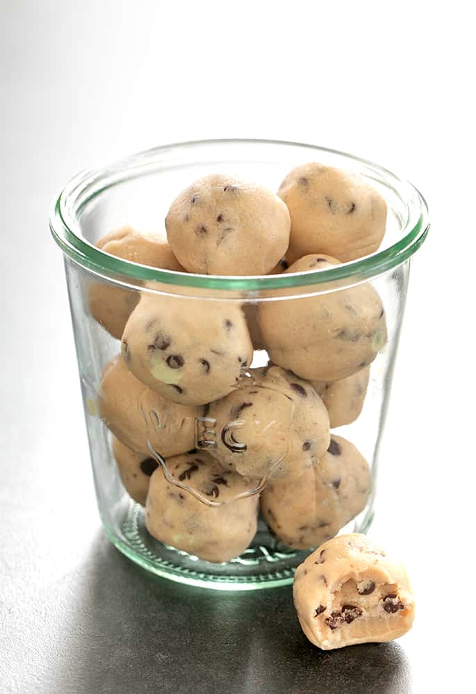 glass mason jar with light brown gluten free edible cookie dough balls on black surface