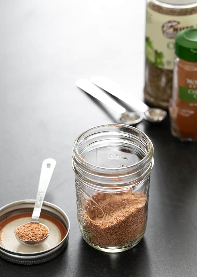 Gluten free taco seasoning in jar, with a teaspoonful beside the jar. 