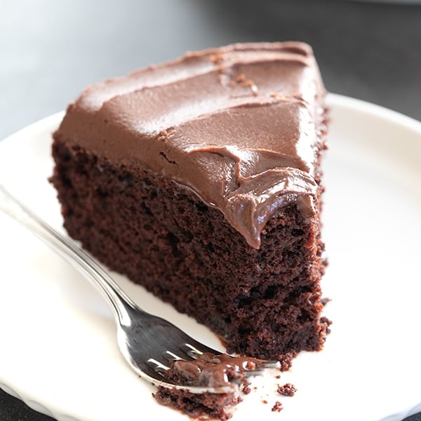 slice of single layer chocolate cake with chocolate frosting on white plate with fork