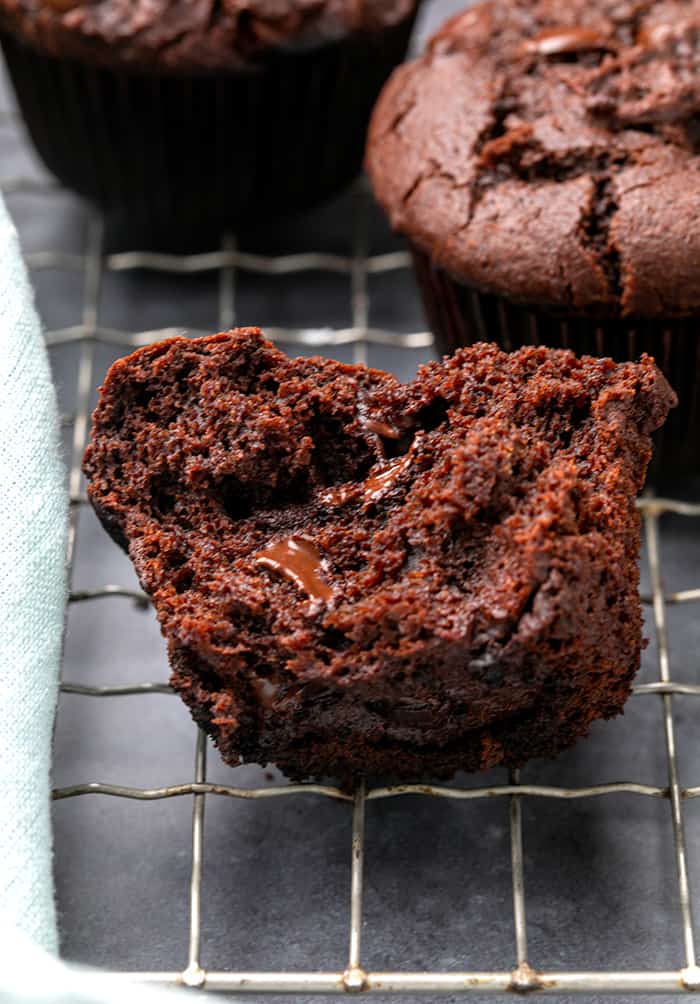 Dark brown gluten free chocolate muffin broken in half on wire rack