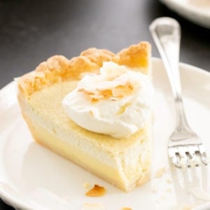 closeup image of slice of gluten free coconut cream pie with whipped cream and coconut pieces
